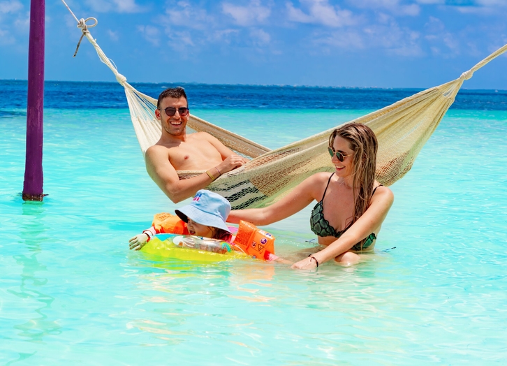 Family in a hammock over the turquoise water at Grand Oasis Palm