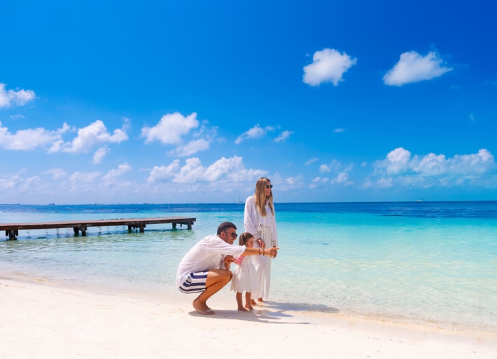 Family at the white sand shore facing the Caribbean Sea at Grand Oasis Palm