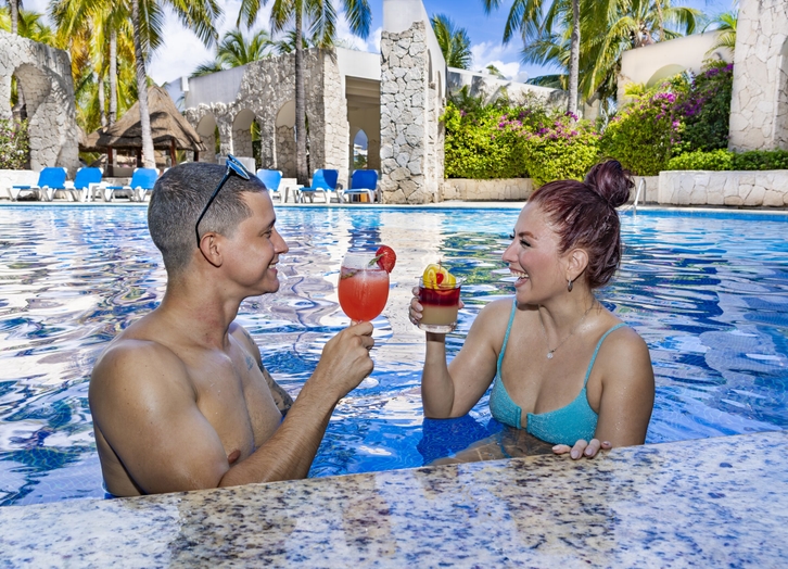 Couple toasting with cocktails at the swim-up bar at Grand Oasis Palm
